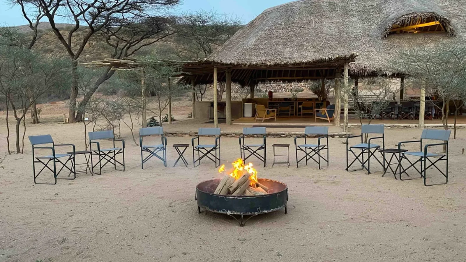 Fire pit and outdoor seating in front of the open-sided lodge at Koros Camp