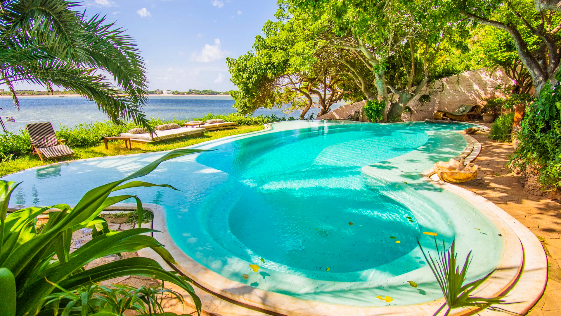 Swimming pool surrounded by tropical gardens overlooking the ocean at Peponi Hotel, Lamu.