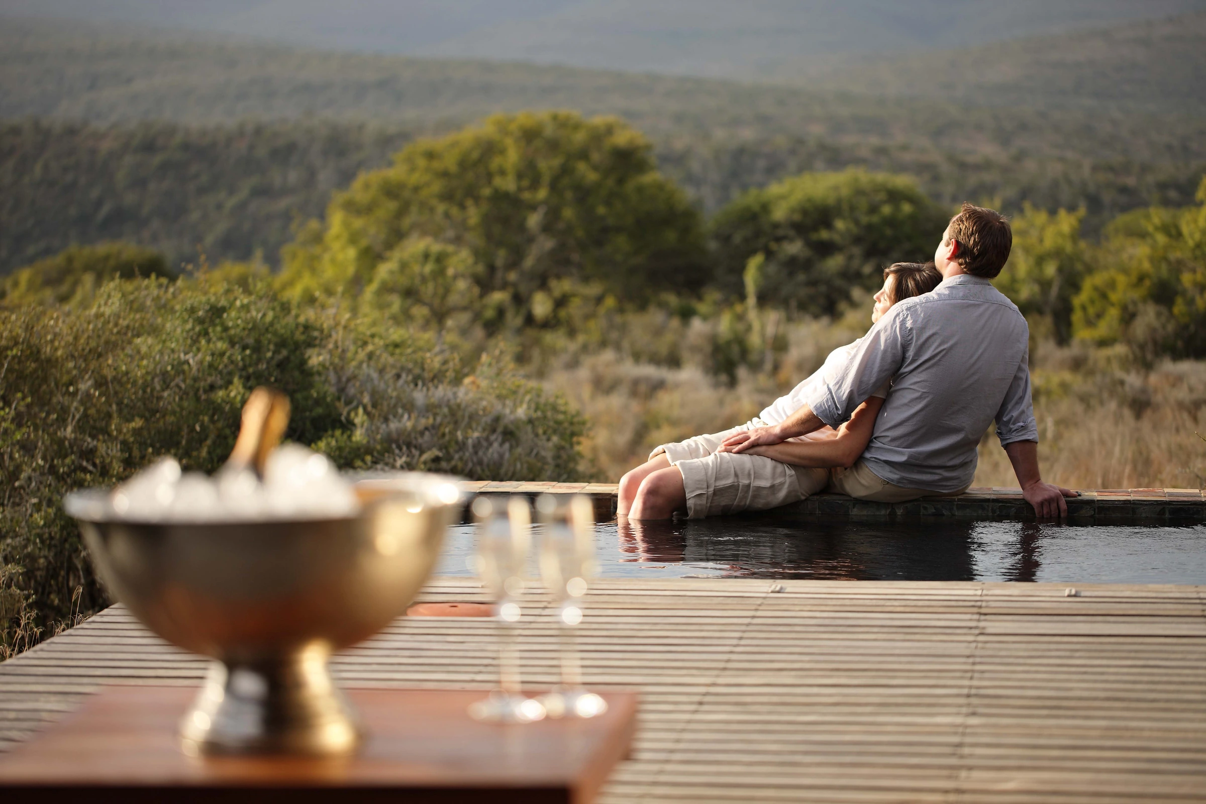 Couple sitting at the edge of a private pool overlooking the bush at Kwandwe Private Game Reserve, South Africa