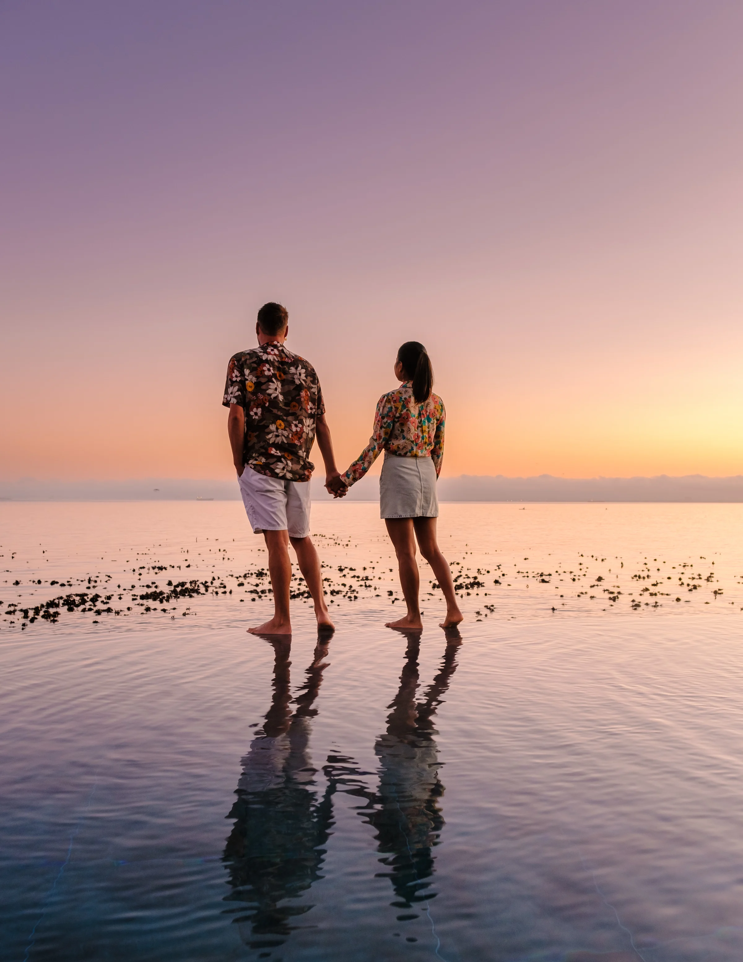Couple standing beside an infinity pool at sunset